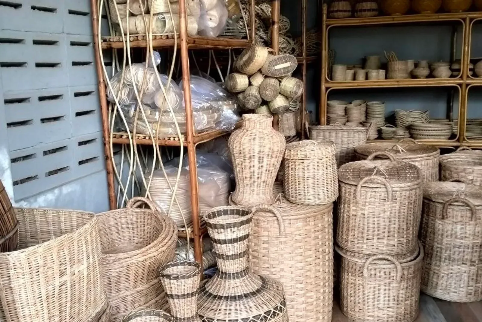 Shelving unit stacked with rattan baskets, woven vases and rolled mats in the shop
